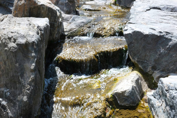 flujo de arroyo de agua dulce con grandes rocas de roca y piedras de cerca foto de paisaje. imagen de fondo natural de la orilla del río rocoso con textura rugosa. pequeño arroyo de cascada con agua brillando al sol - boulder flowing water mountain range rock fotografías e imágenes de stock