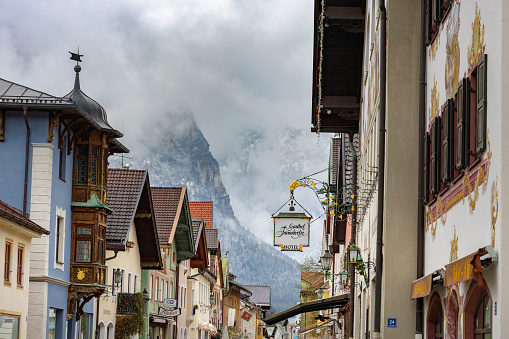 Garmisch Partenkirchen, Germany - 04.10.2022: typical decorated bavarian Ludwig street in Garmisch Partenkirchen Gasthof Fraundorfer mountain background .