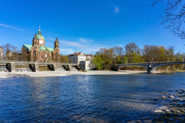 Isar river in Munich with saint Lukas dome cathedral and bridge