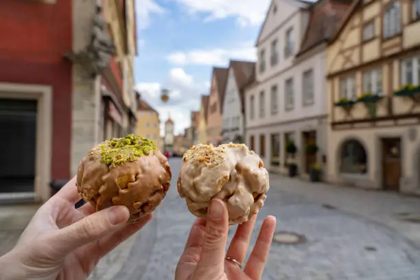 eating traditional schneeball snowball cake together the cake of the romantic Rothenburg ob der Tauber with timbered Fachwerkhaus syle houses in Bavaria Germany .