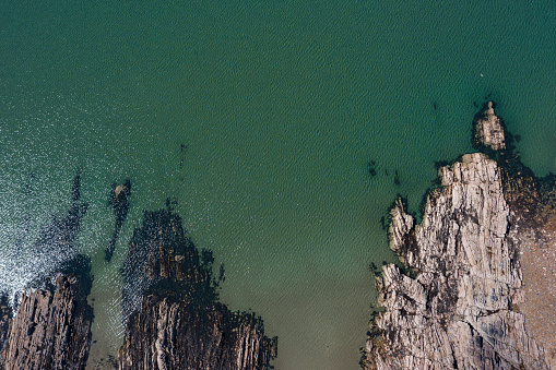 Looking directly down on to a section of rocky coast from a drone on a bright summer morning