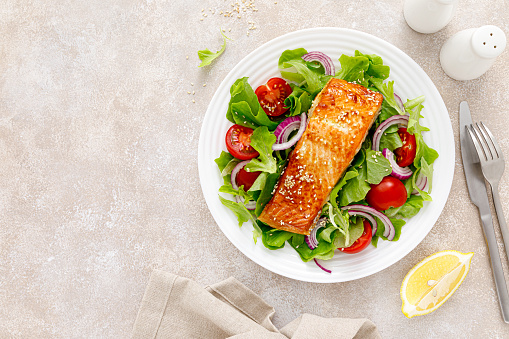 Grilled salmon fish fillet and fresh vegetable salad with tomato, red onion and lettuce