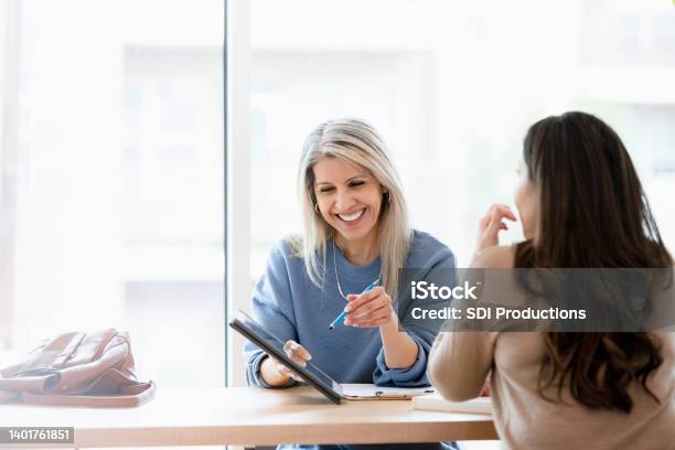 Female Financial Advisor Reviews Documents On Digital Tablet Stock Photo - Download Image Now