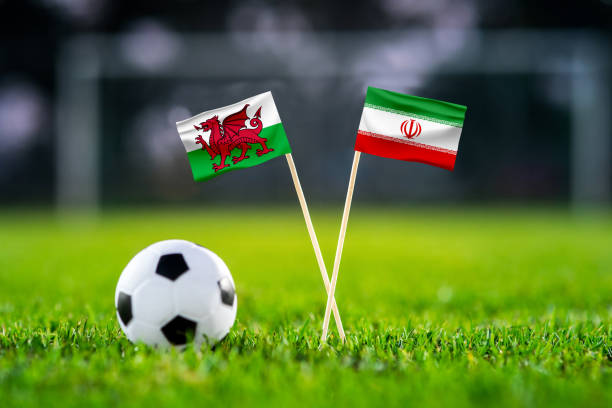 уэльс vs. иран, ахмад бин али, обои футбольного матча, национальные флаги ручной работы и футбольный мяч на зеленой траве. футбольный стадион  - iran wales стоковые фото и изображения