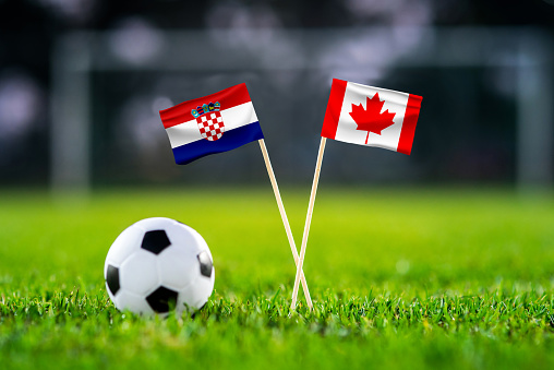 Croatia vs. Canada, Khalifa Stadium, Football match wallpaper, Handmade national flags and soccer ball on green grass. Football stadium in background. Black edit space.
