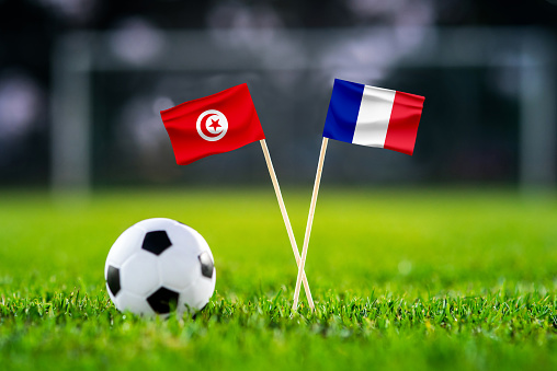 Tunisia vs. France, Education City, Football match wallpaper, Handmade national flags and soccer ball on green grass. Football stadium in background. Black edit space.