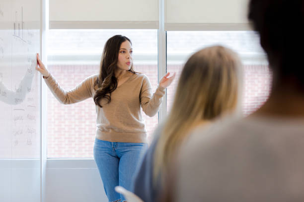 istock Casually dressed businesswoman presents finances to unrecognizable team 1401763623