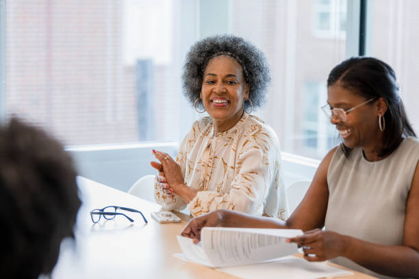 Senior CEO smiles as female assistant reviews documents