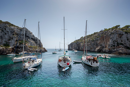 Alaior, Spain - August 8, 2021: Sailing boats anchored in Cales Coves, a famous cove in the municipality of Alaior, Menorca, Spain