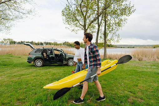 Photo of a smiling couple preparing things for kayaking on the lake.