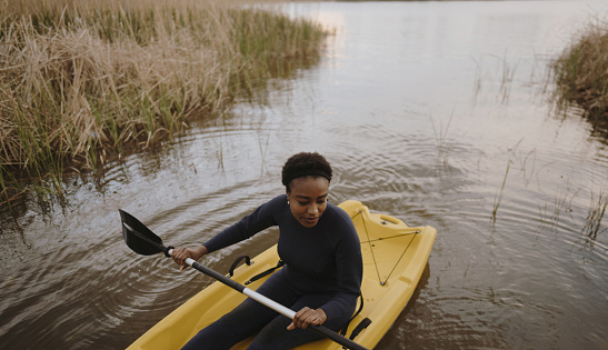 Photo of a young woman enjoying kayaking in the dusk.
