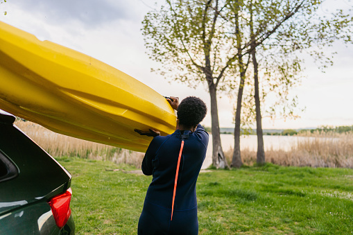 Photo of a young woman carrying her kayak.
