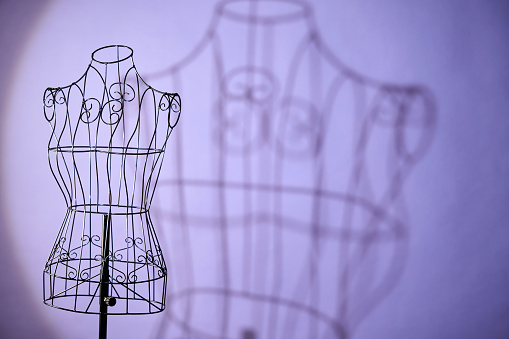 wire mannequin with  shadow against purple background