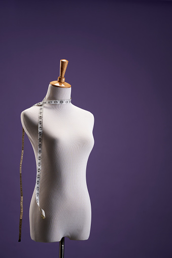 deskmaker's mannequin with tape measure against purple background