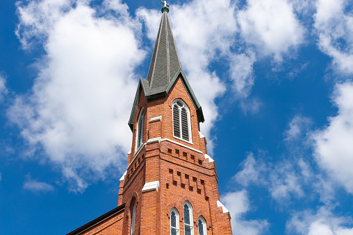 Beautiful brick church in small Midwest town with blue skies and clouds in the background.