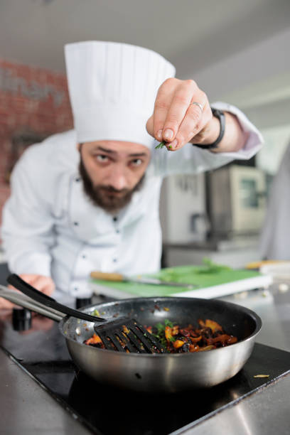 istock Gastronomy expert throwing fresh chopped herbs in pan while cooking gourmet dish for dinner service at restaurant 1401771927
