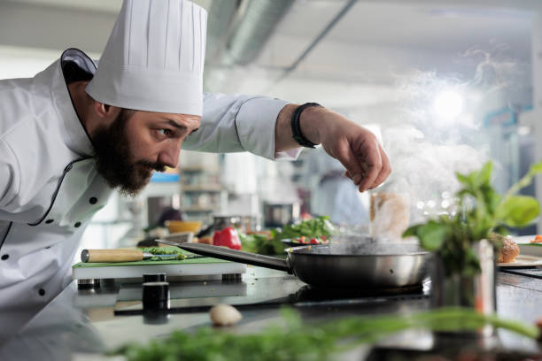 istock Food industry worker preparing ingredients for meal while seasoning vegetable stew with herbs and spices 1401772013
