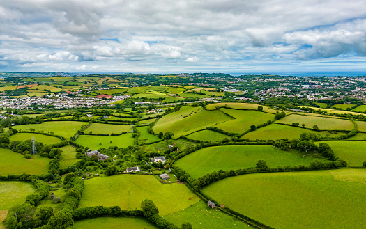 A stunning series of 6 images of English farmland in the Vale of Evesham at the northern extreme edge of the Cotswolds in the English Midlands. The shoot was made in mid-October 2019 in late afternoon autumn sunlights and the muted colours of browns, golds and greens under expansive blue skies with dappled cloudscapes perfectly compliment each other. The patchwork of ploughed or harrowed fields, hedgerows and mature deciduous trees are archetypal English Pastoral scenes of the kind so popular with 18th Century artists like Constable and these atmospheric images evoke the same timeless qualities as those paintings. This fourth picture in the series is a telephoto image of the patchwork andscape of fileds in the far distance. The compressed focal length and the criss-crossing of the hedgerows and trees above the bright green or brown ploughed fields emphasises the pastoral nature of this iconic landscape.