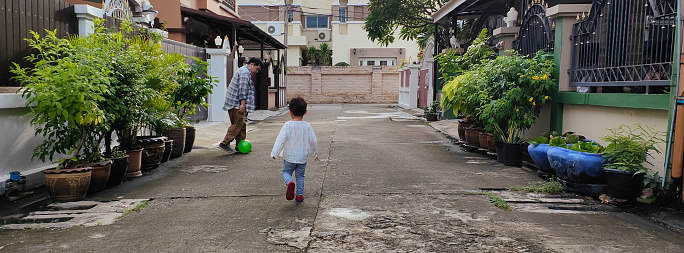 Young father with his little son playing football on street outdoor