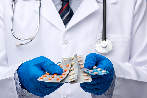 Male doctor holding different pill tablets in his hand