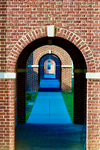 Arch in an old red brick wall with a white background