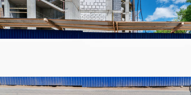 istock Large blank information banner fixed on blue steel fence of construction side. 1401779025