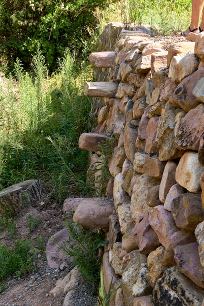 kamienna ściana dla pól z kamiennymi schodami do wspinaczki, otoczona roślinnością. - cornerstone sign built structure granite zdjęcia i obrazy z banku zdjęć