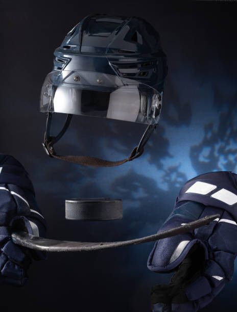 Closeup of ice hockey equipment against a dark background. Ice hockey helmet, stick, puck and gloves stock photo