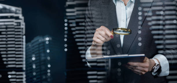 a woman looks through a magnifying glass at a document . - loupe quality control magnification glass imagens e fotografias de stock