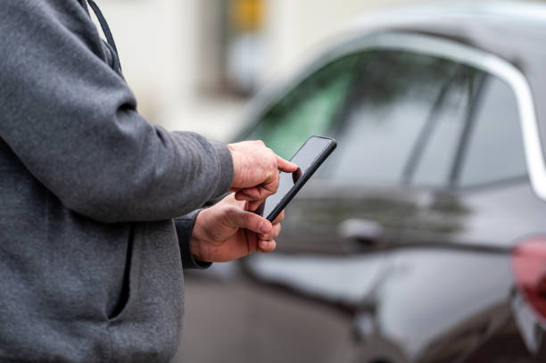 istock man with smartphone standing next to the car, using mobile app for paying, car lock  or Internet 1401782262