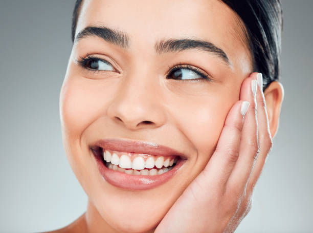 istock A beautiful young mixed race woman with glowing skin posing against grey copyspace background. Hispanic woman with natural looking eyelash extensions smiling while feeling her smooth skin in a studio 1401784801