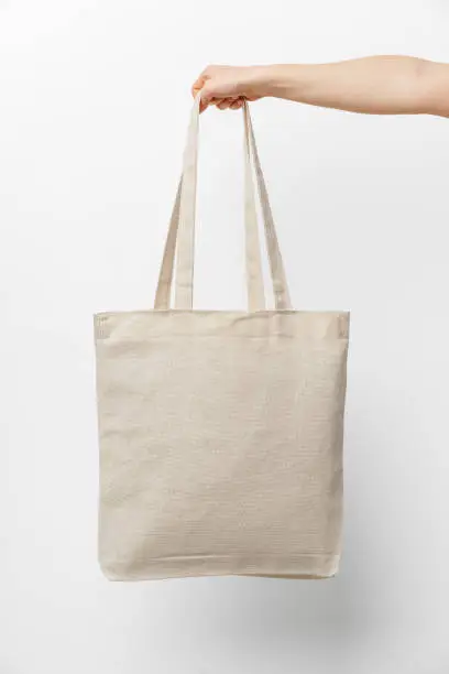 Photo of Female hand holding eco or reusable shopping bag against white background