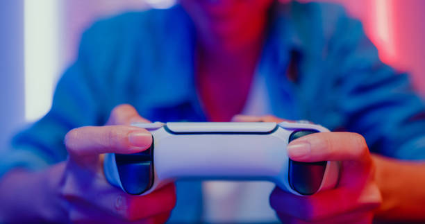自宅のネオンライトのリビングルームでビデオゲーム機をプレイしている若いアジア人女性のクローズアップ。 - video game joystick leisure games control ストックフォトと画像