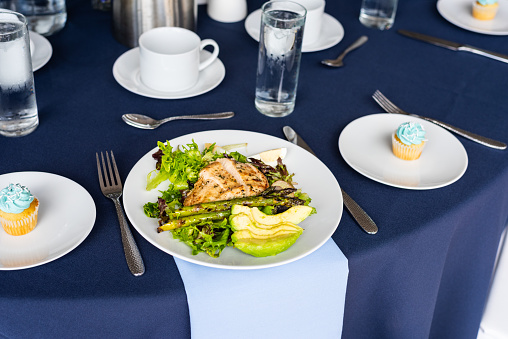 Avocado chicken salad and cupcakes on white plates and formal dining blue table cloth table setting