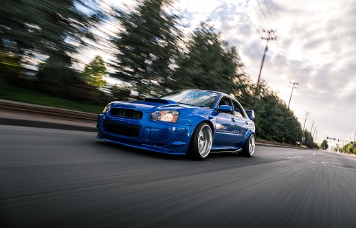 Seattle, WA, USA
5/22/2022
Blue Subaru WRX driving on the street with a power line overhead and trees in the background