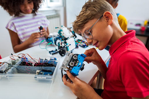 A group of cheerful tweens in a classroom, making robots for a school competition