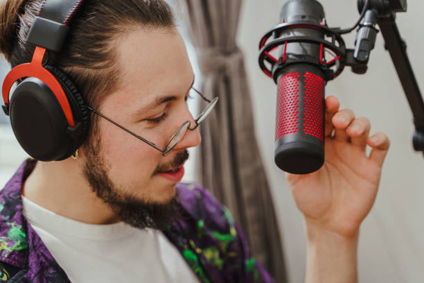 istock Young man blogger using headphones and condenser microphone  during online podcast stream 1401794028
