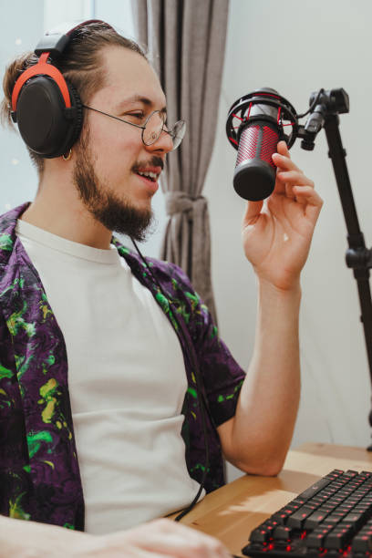 istock Young man blogger using headphones and condenser microphone  during online podcast stream 1401794034
