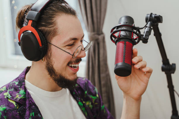 istock Young man blogger using headphones and condenser microphone  during online podcast stream 1401794053