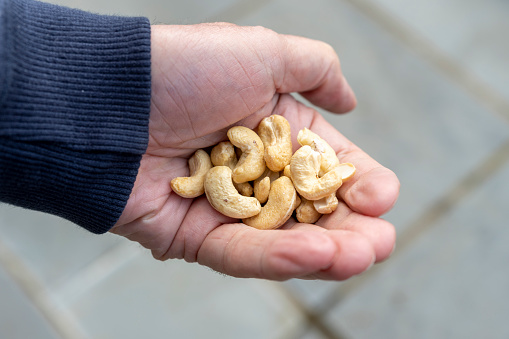 Senior man holding a handful of cashew nuts.