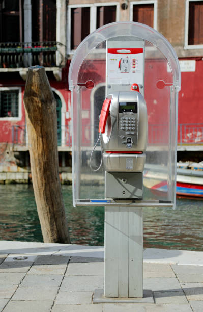 Venice, VE, Italy - May 18, 2020: old italian phone box and the navigable canal on background