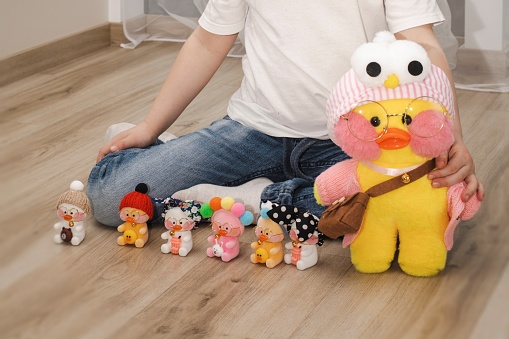 The child plays on the floor with toys. Lots of beautiful stuffed toys. Cute modern popular toys