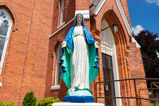 Statue of the Virgin Mary with brick church in the background.