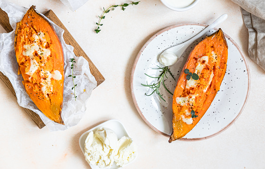 Baked sweet potatoes with mozzarella, herbs and creamy dip on concrete background.