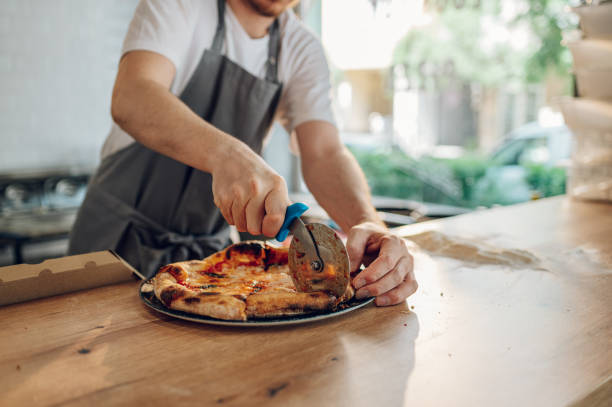 istock Hand of kitchen chef cutting pizza with a pizza cutter 1401807610