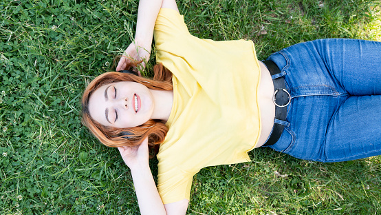 Relaxed woman lying on the grass listening to music