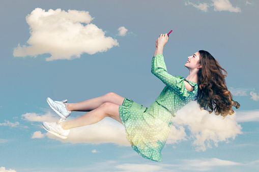 Hovering in air. Happy girl in dress levitating with mobile phone, reading message chatting happy joyful in social network online, surfing web while flying. collage composition on day cloudy blue sky