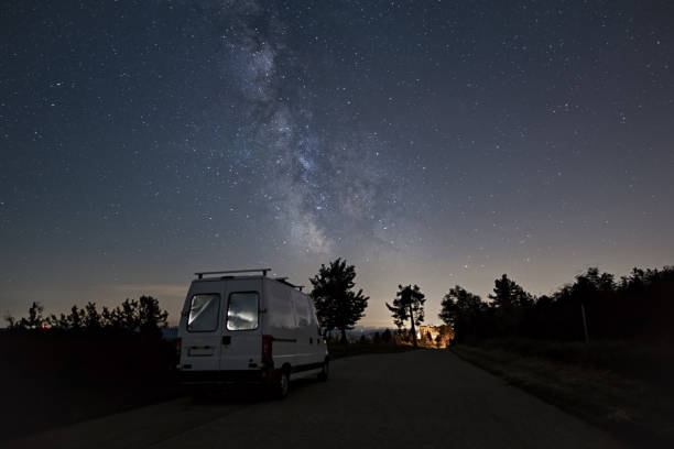 istock Milky Way over illuminated camper van and silhouette of trees, Black Forest, Germany 1401808422