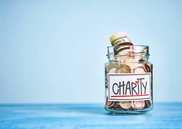 Photo of Charity donation money jar with blue background and space for text