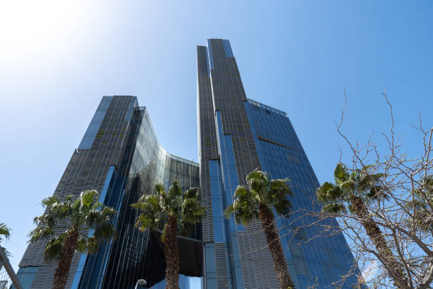 istock Modern tall office building made from steel and glass with palm trees at front. Low angle view 1401819311